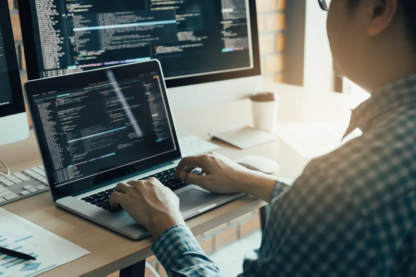 man coding on a laptop and pc
